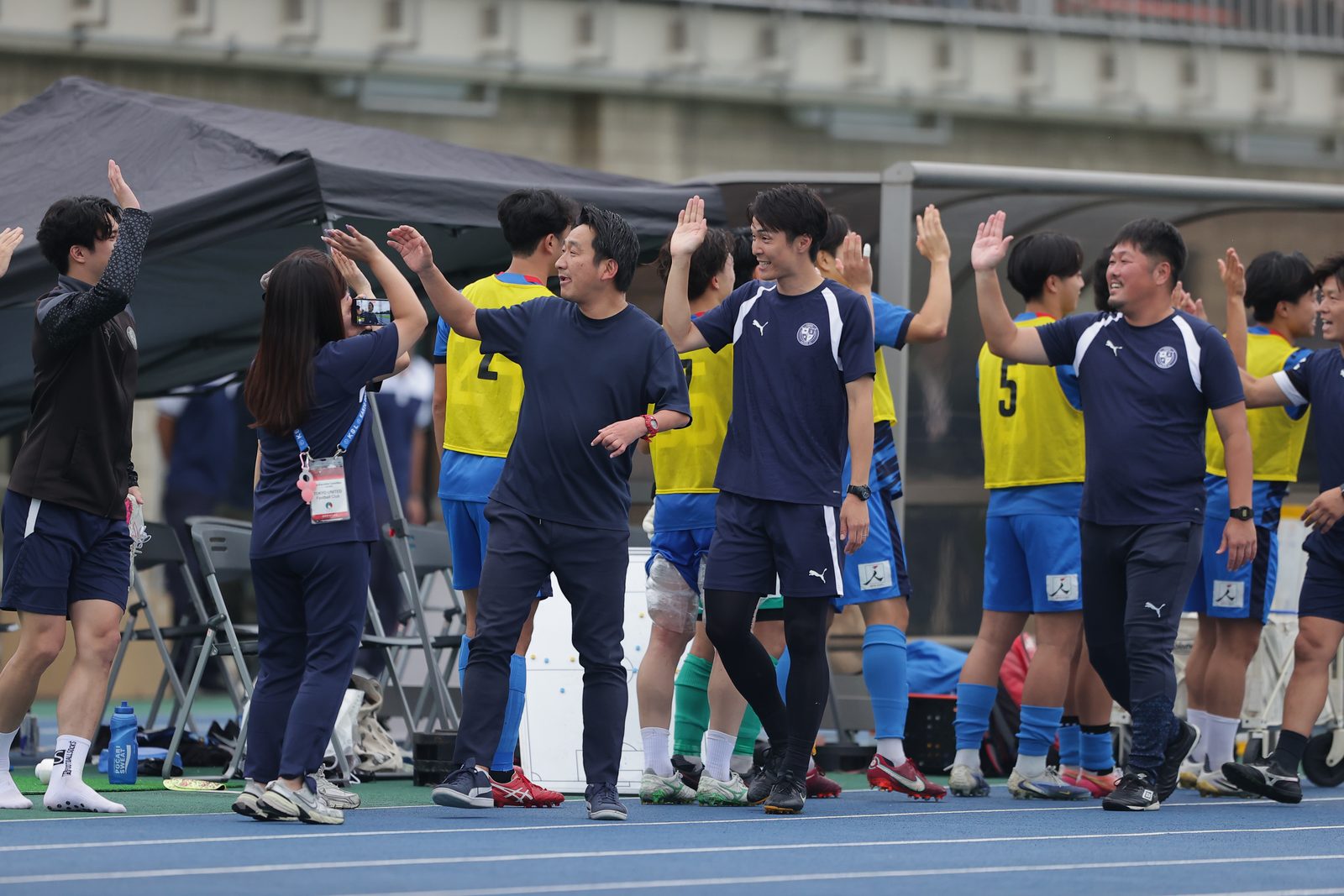 ベンチ前で喜びを分かち合う東京ユナイテッドFCの選手・スタッフ